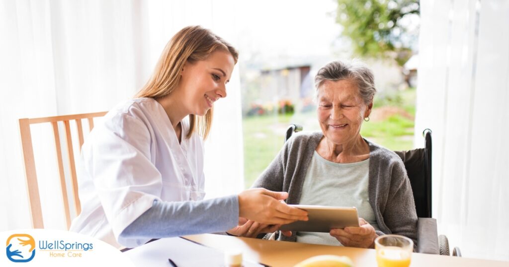 A professional caregiver smiles as she helps a happy senior client with her tablet, showing that she is managing caregiving stress well.